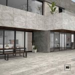 Piso ceramico gres color grey-60x120-mate-interior-exterior-amsterdam-castel-2-ok | Plomería García Modern stone-clad building with large glass doors, outdoor picnic table, and potted plants.